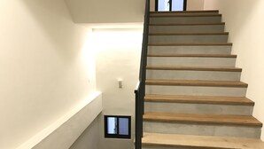 A staircase with wooden steps and a black railing, leading to a landing with a small window. - Welcome Hostel (Hualien City)