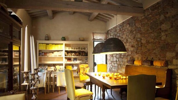 A dining area with a stone wall, wooden ceiling beams, and a table set for four. - Casa Osteria (Lucca)
