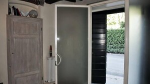 A room with a wooden door, a glass door, and a view of a hedge outside. - Casa Osteria (Lucca)