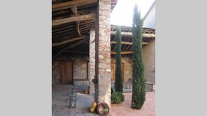 An outdoor area with stone pillars, a wooden ceiling, and a brick floor. - Casa Osteria (Lucca)
