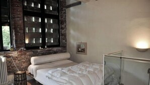 A bedroom with a bed, a radiator, a window with blinds, and a picture on the wall. - Casa Osteria (Lucca)