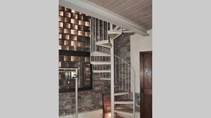 A spiral staircase with a metal railing, a stone wall with a brick pattern, and a wooden door. - Casa Osteria (Lucca)