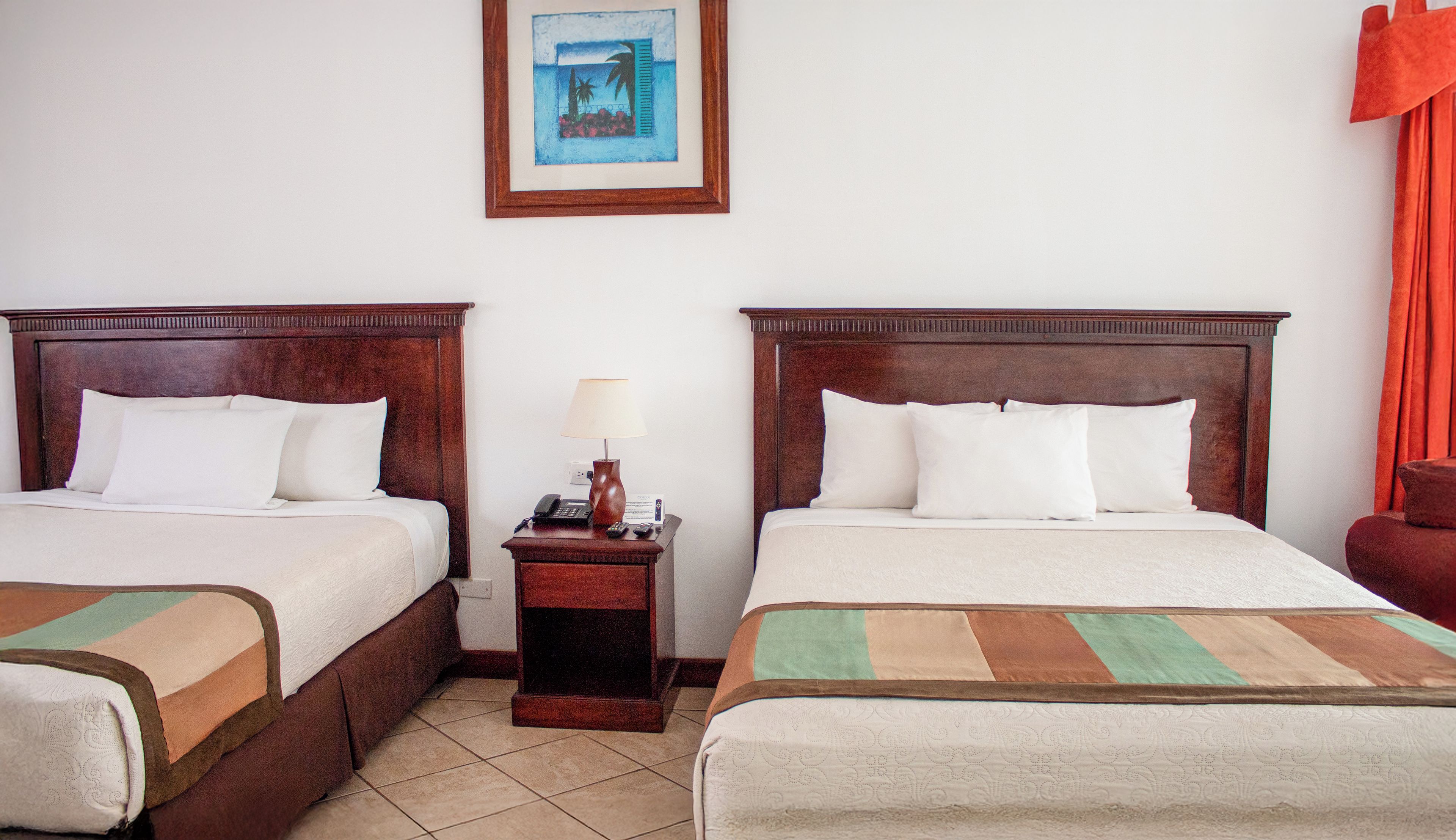 Habitació d'hotel amb dos llits, una petita taula de nit amb una làmpada i un quadre al mur.