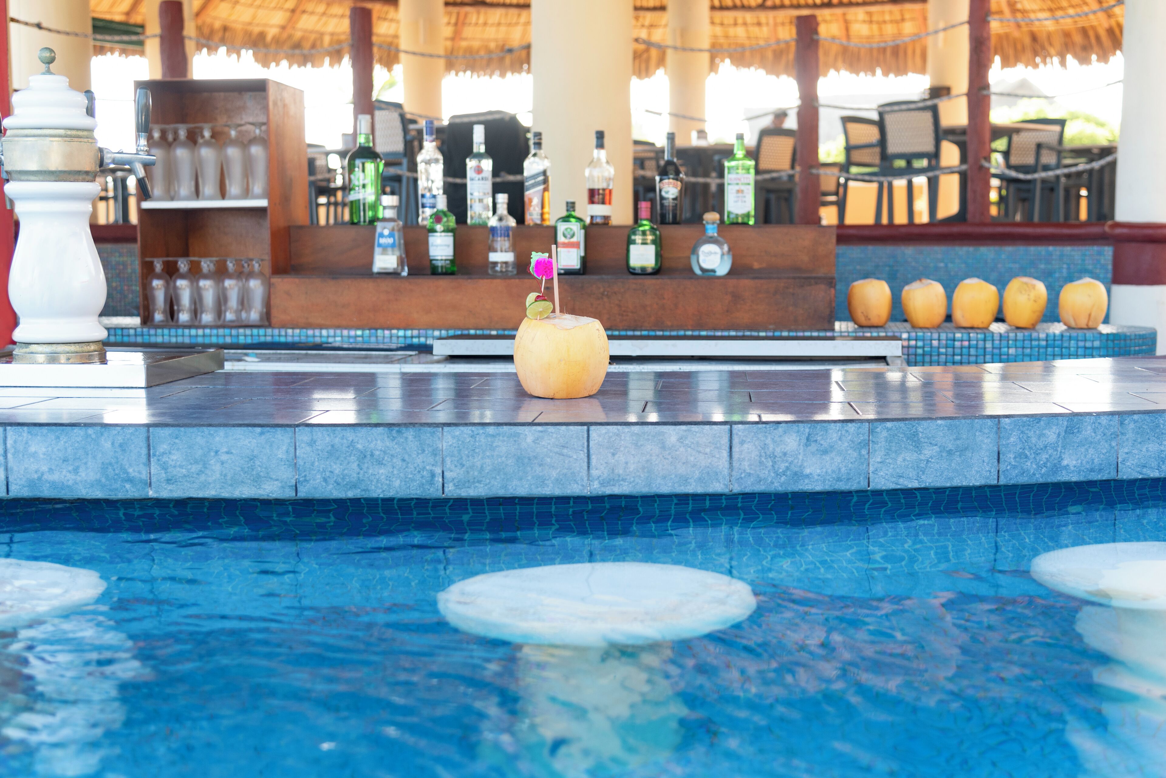 A poolside bar area with a tiki drink, a bar counter, and a row of bottles.