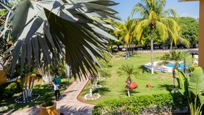 Un jardín ajardinado con palmeras, un sendero y una zona de piscina.