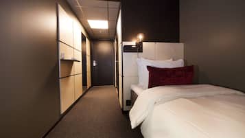 Una habitación de hotel con cama, mesita de noche, armario y un pasillo que lleva a otra habitación.
