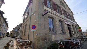 Un edificio con un letrero que dice 'Café Hôtel Resto' y terraza.