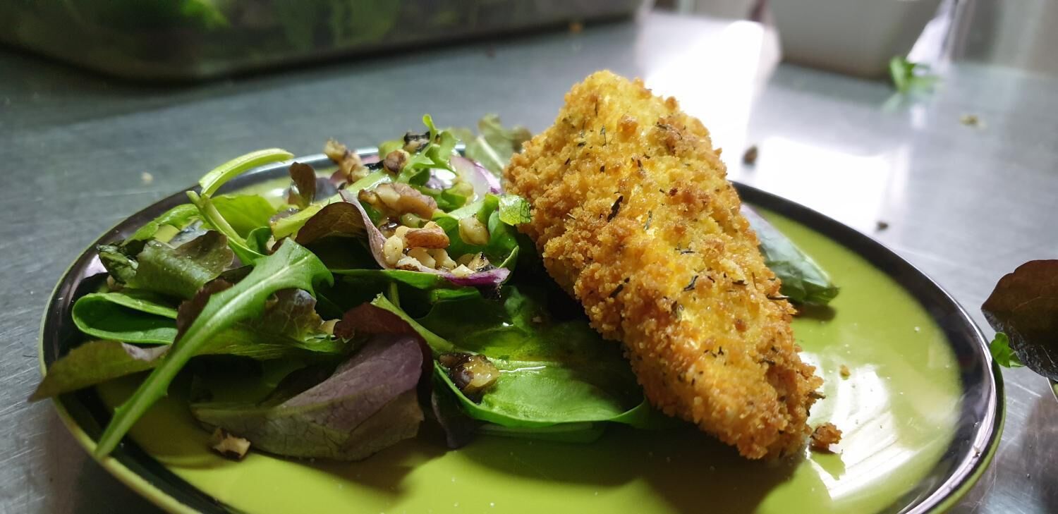 A plate with a breaded item and a salad.