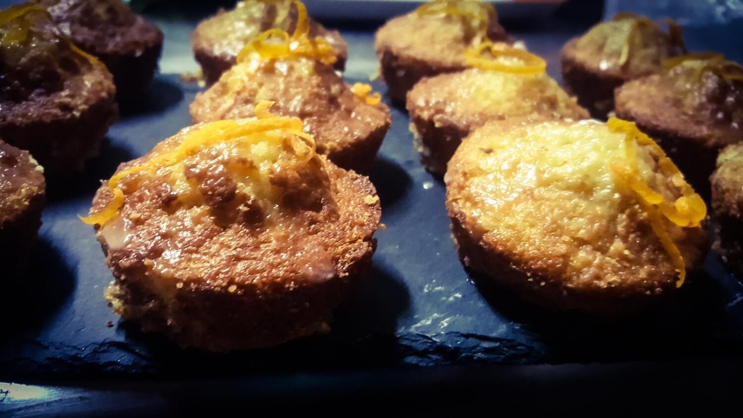 A tray of muffins with a golden-brown crust and a yellow topping.