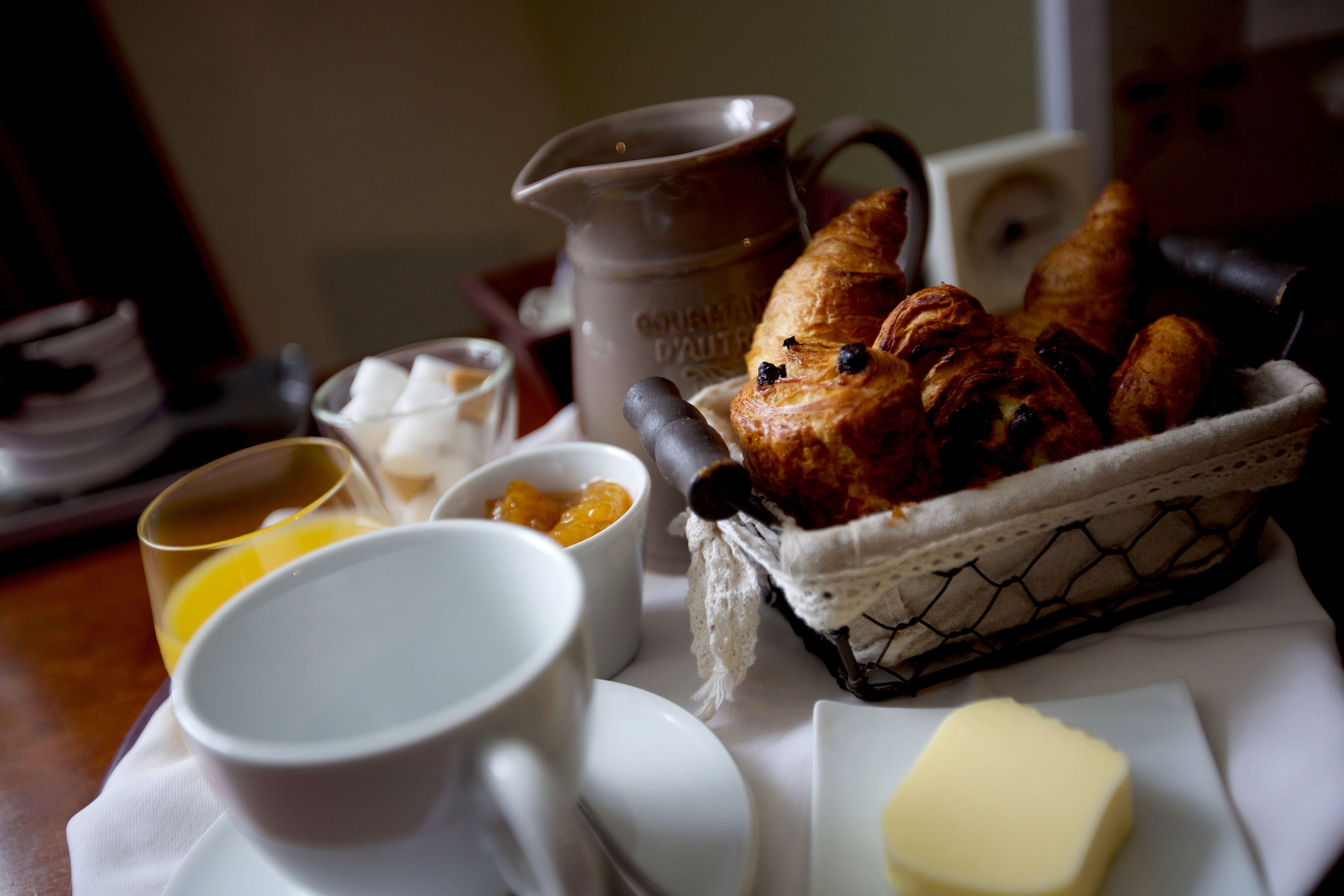 Ein Frühstückstisch mit Croissants, einer Kanne und einem Korb mit Brot.