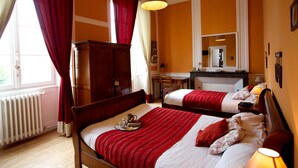 Una habitación de hotel con dos camas, un armario de madera, un escritorio y un espejo.