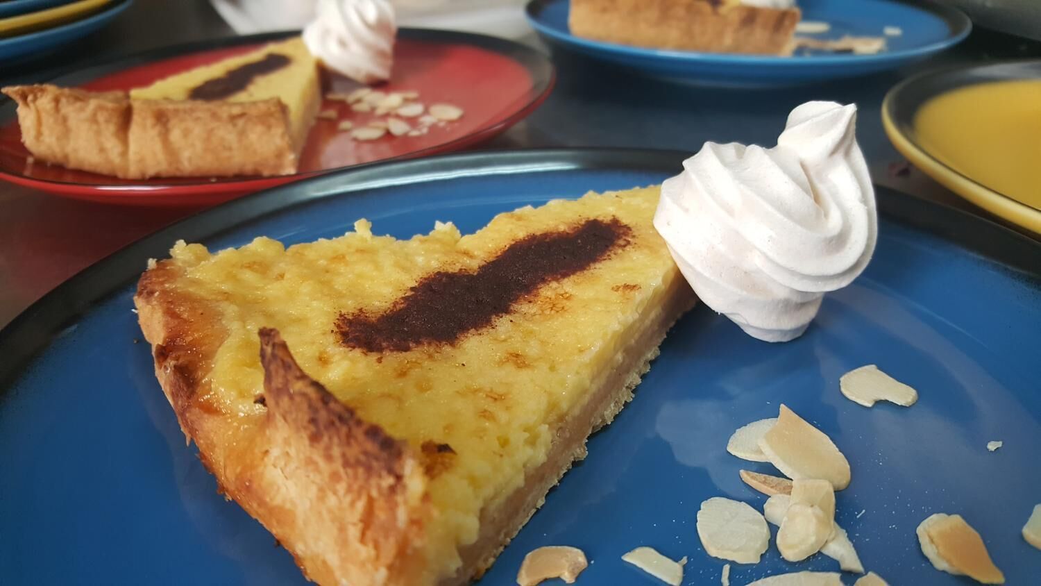 A slice of cake with whipped cream and almonds on a blue plate.