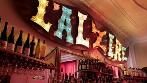 Un bar con letras iluminadas que deletrean "CALLE" y estantes llenos de botellas y vasos.