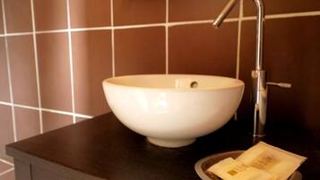 Un lavabo bianco su un piano d'appoggio scuro, con un rubinetto e un vassoio contenente un fazzoletto e una piccola confezione.