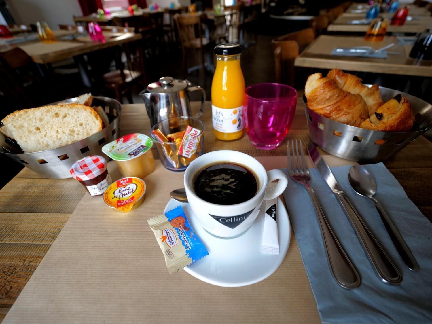 Ein Frühstückstisch mit Brot, Croissants, Kaffee und Beilagen.