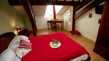 Une chambre avec une couvre-lit rouge, un plateau de petit-déjeuner sur le lit, un bureau en bois et une chaise dans un coin.