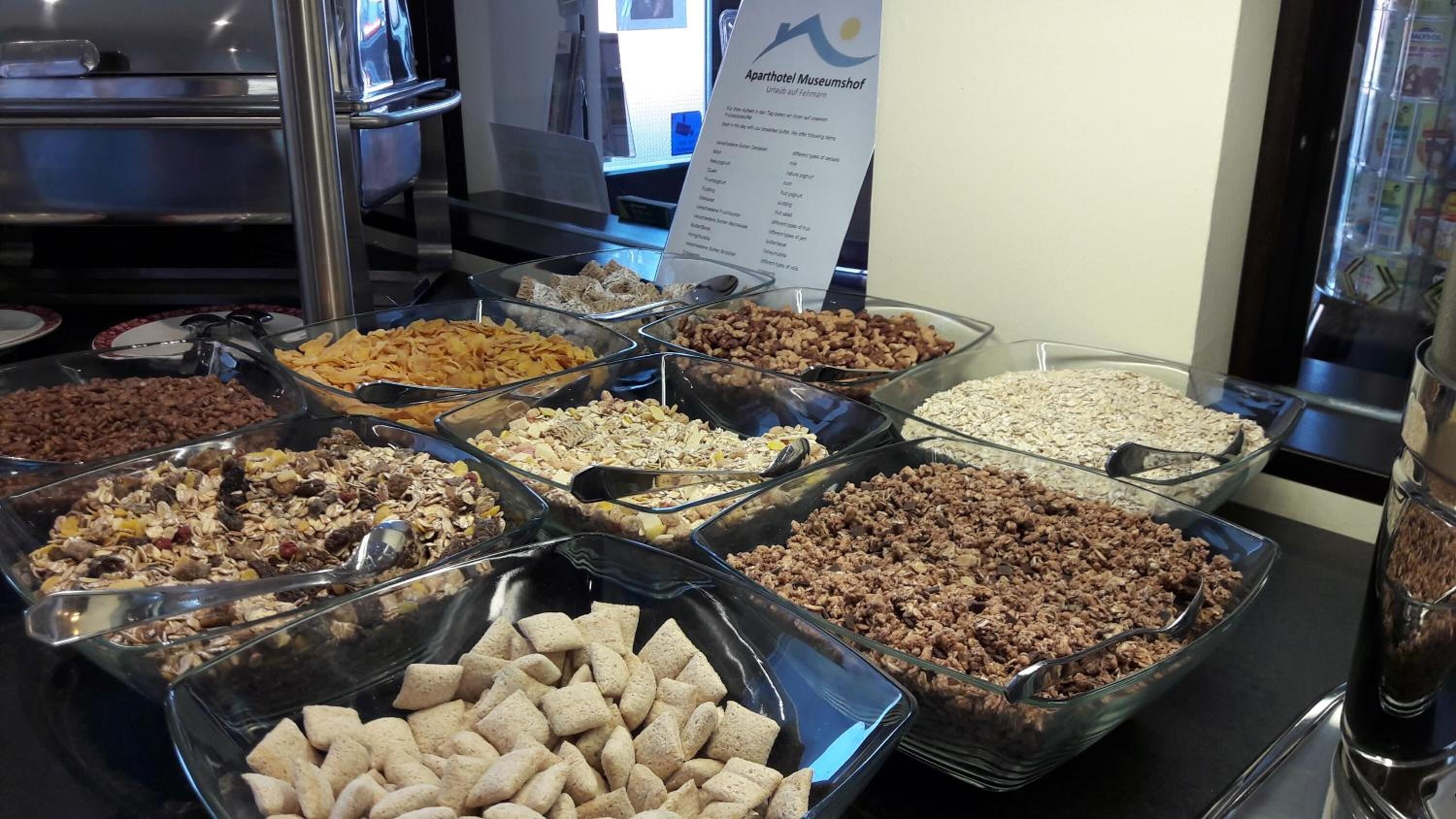 En buffet med forskellige spisemuligheder, heriblandt müsli, nødder og granola.