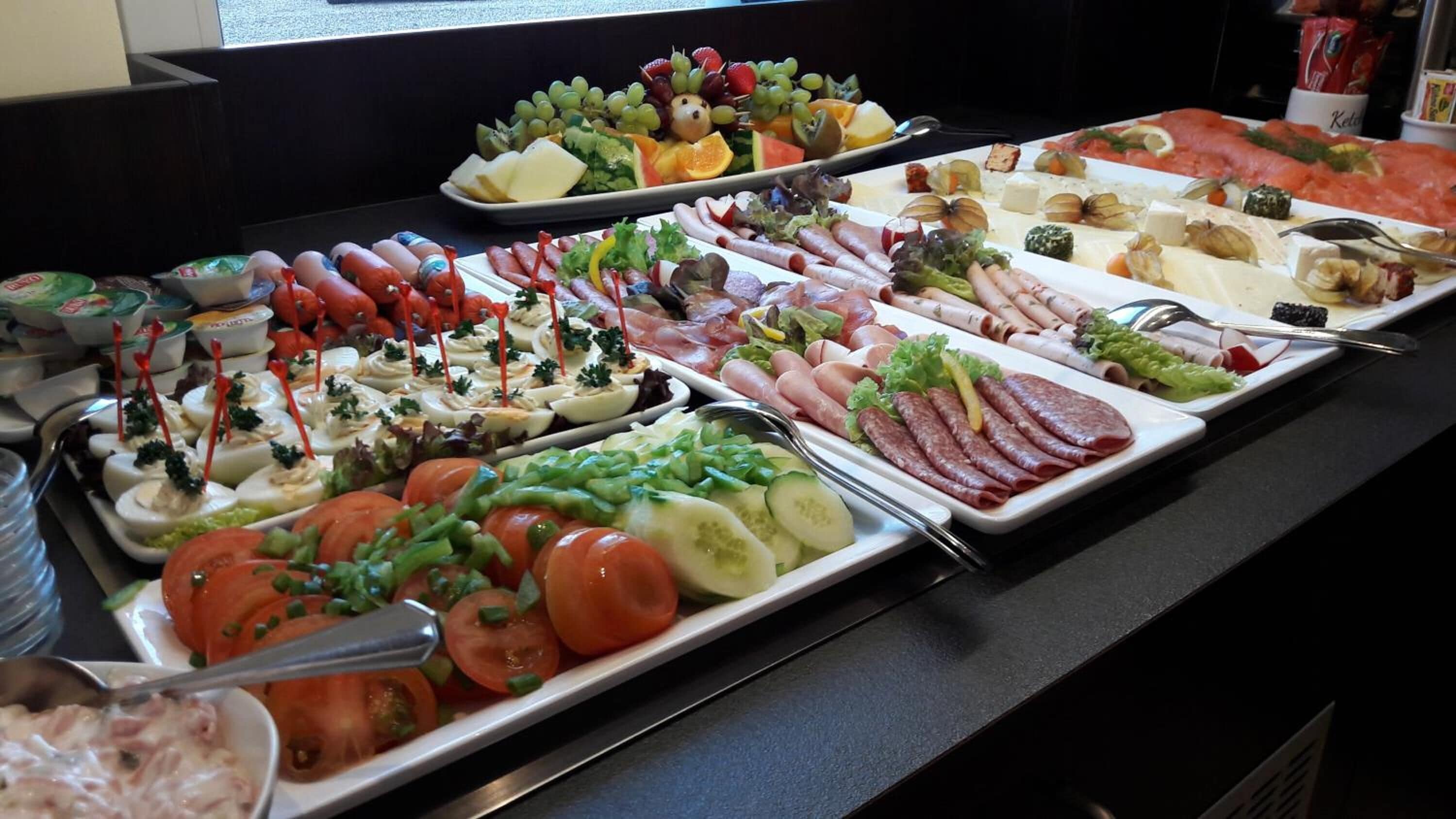 En buffé med ett varierat utbud av mat, inklusive kött, ostar och grönsaker.