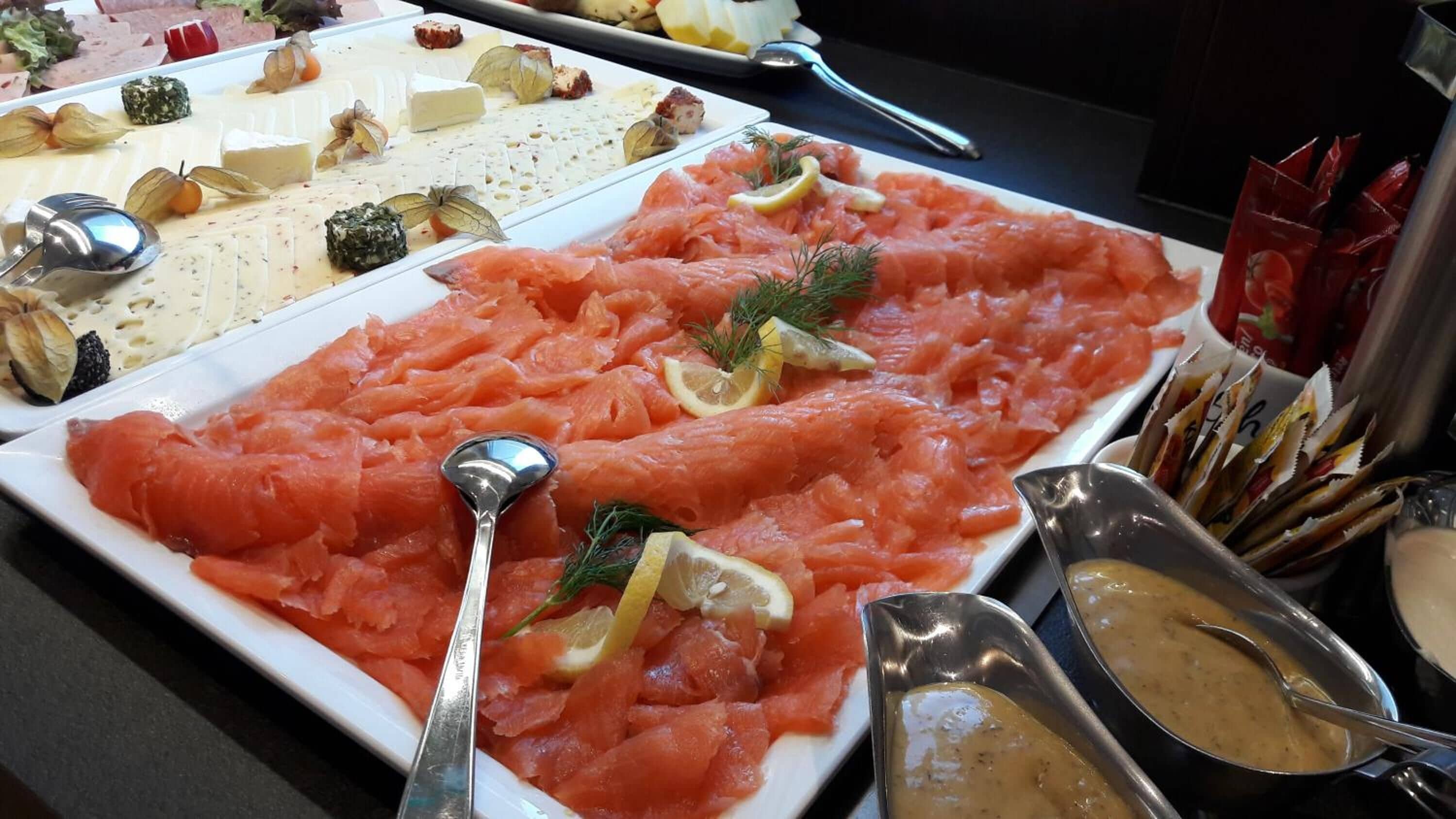 A buffet with various food items including salmon, cheese, and other dishes.