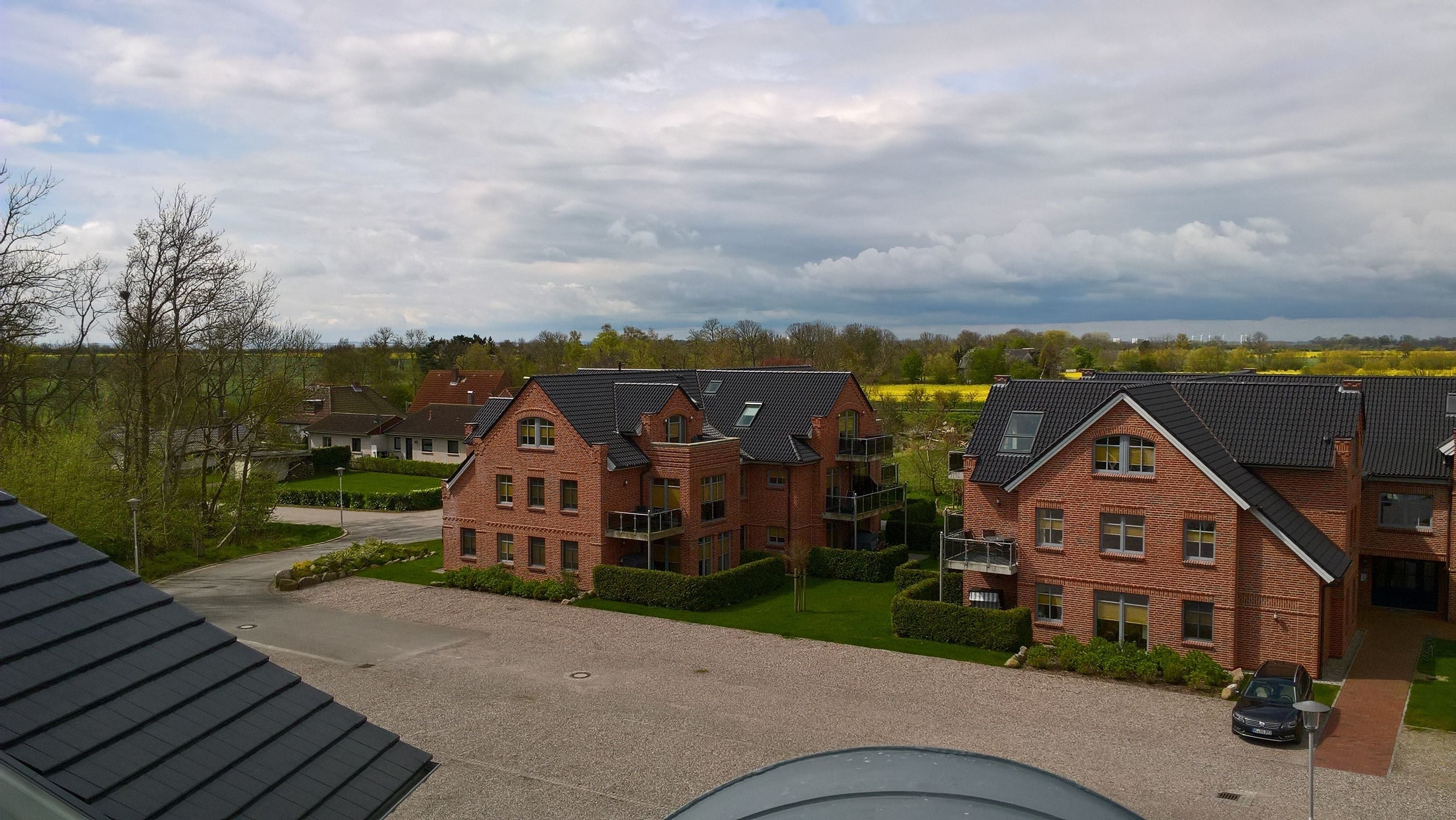 Een woonwijk met bakstenen huizen, een grindpad en een auto die ervoor geparkeerd staat.
