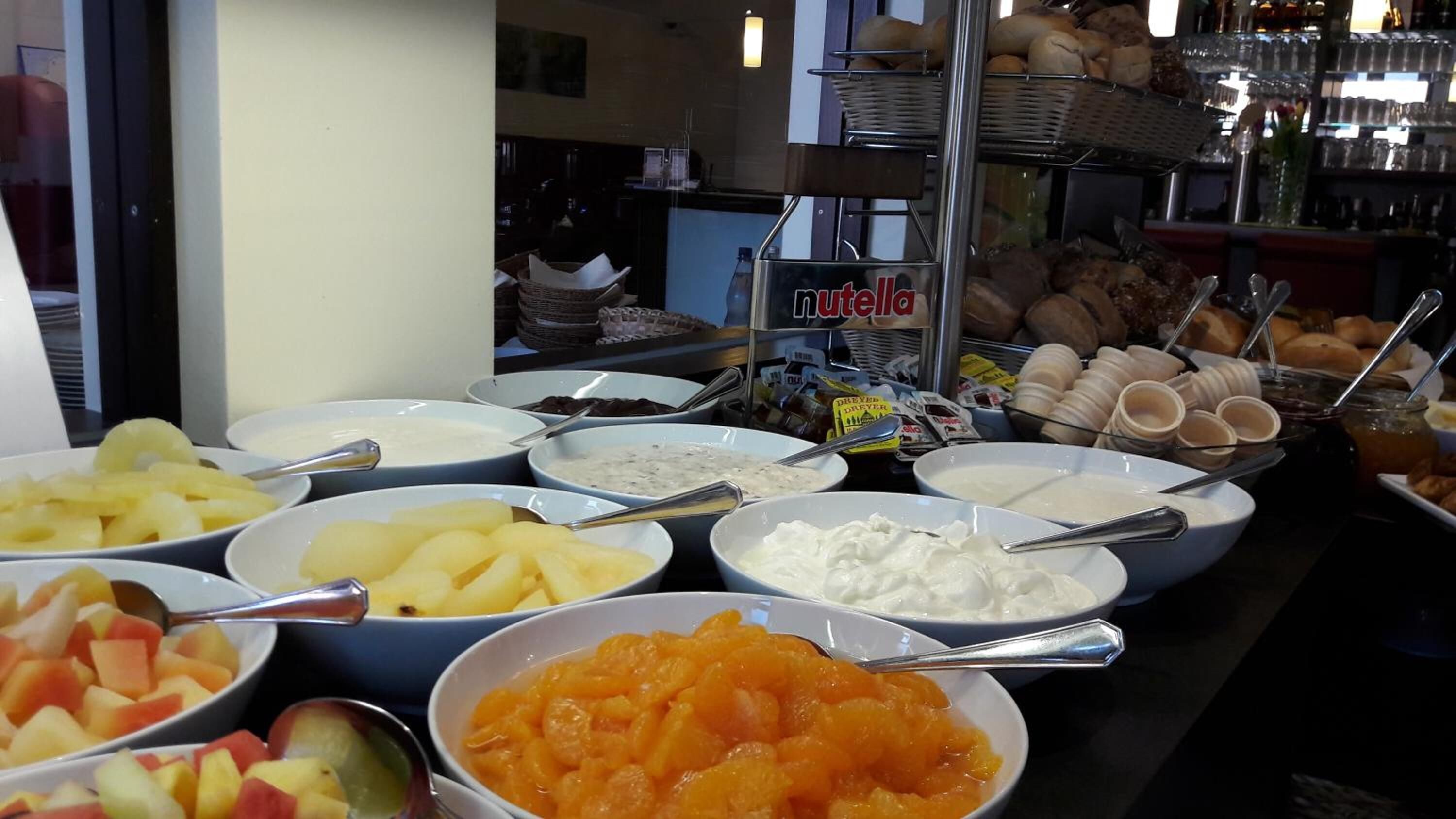 A buffet with various food items including fruits, yogurt, and pastries.