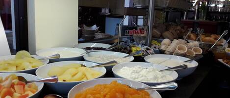 A buffet with various food items including fruits, yogurt, and pastries.