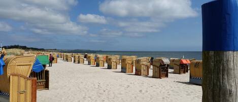 Una playa con hileras de cabañas de mimbre.