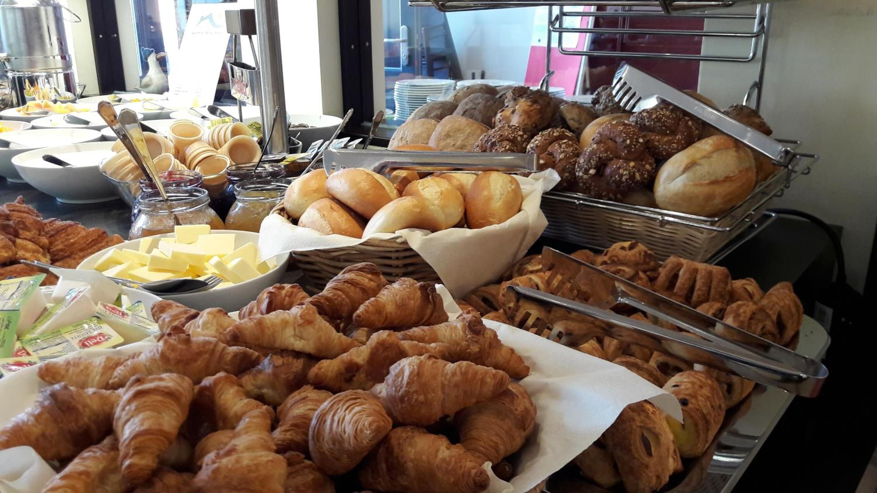 A buffet with various baked goods, including croissants, bread, and pastries.