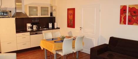 A compact living space with a dining area, kitchenette, and a sofa.