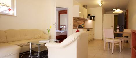 Uma sala de estar moderna com um sofá, uma mesa de centro de vidro e um espaço de jantar com uma cadeira e mesa.