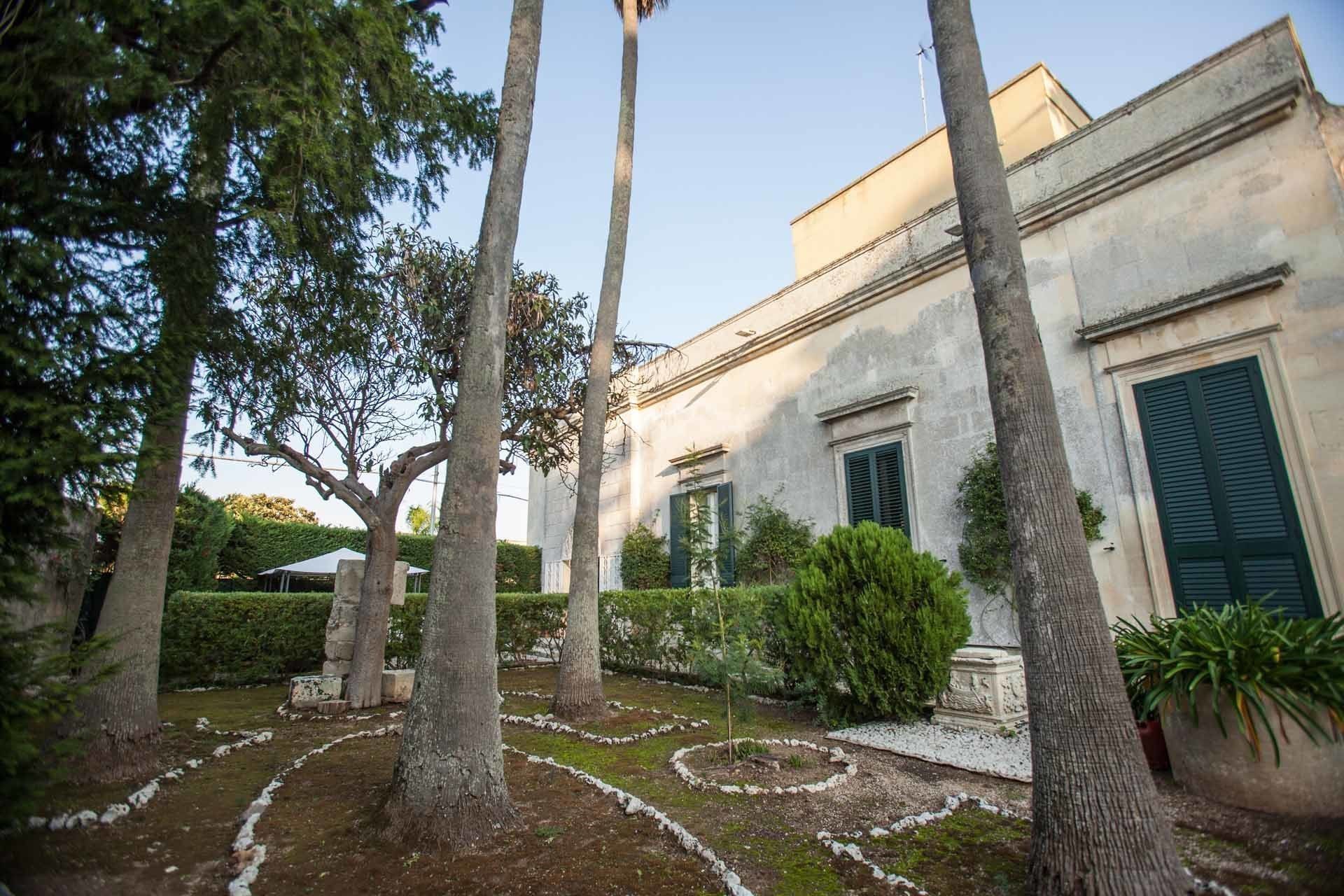 Un bâtiment doté d’un jardin agrémenté d’arbres et d’un sentier circulaire en pierre.