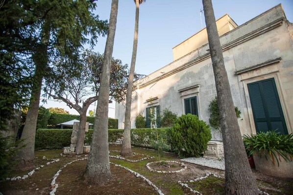 Un edificio con jardín, destacando árboles y un camino de piedra circular.