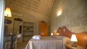 A hotel room with a bed, two bedside lamps, a desk with a computer, a chair, a wardrobe, and a mirror. - Villa De Pietro (Cursi)