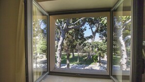 A window with a view of a garden with trees and a pathway. - Villa De Pietro (Cursi)
