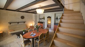 A dining area with a round table, chairs, and a vase of flowers. There is a staircase with wooden steps and a railing. - Villa De Pietro (Cursi)