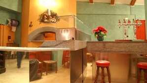 A kitchen with a built-in oven, a bar counter with stools, and a decorative wall piece above the oven. - Hotel Lion (Roure)