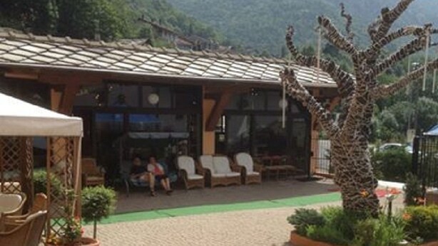 A courtyard with a seating area, a tree, and a building with a tiled roof. - Hotel Lion (Roure)