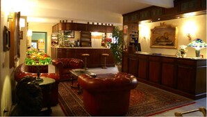 A cozy living room with a fireplace, leather sofa, and a dining area with wooden cabinets and a bar. - Hotel Lion (Roure)