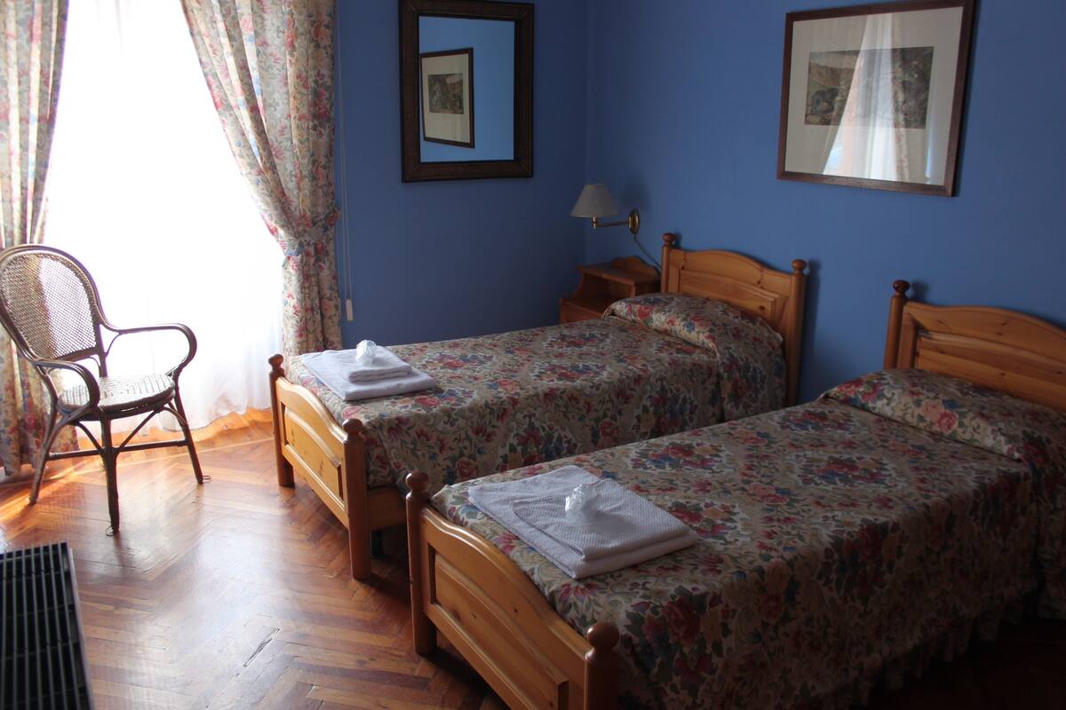 Ein Zimmer mit zwei hölzernen Betten, einem Stuhl und einem kleinen Tisch.