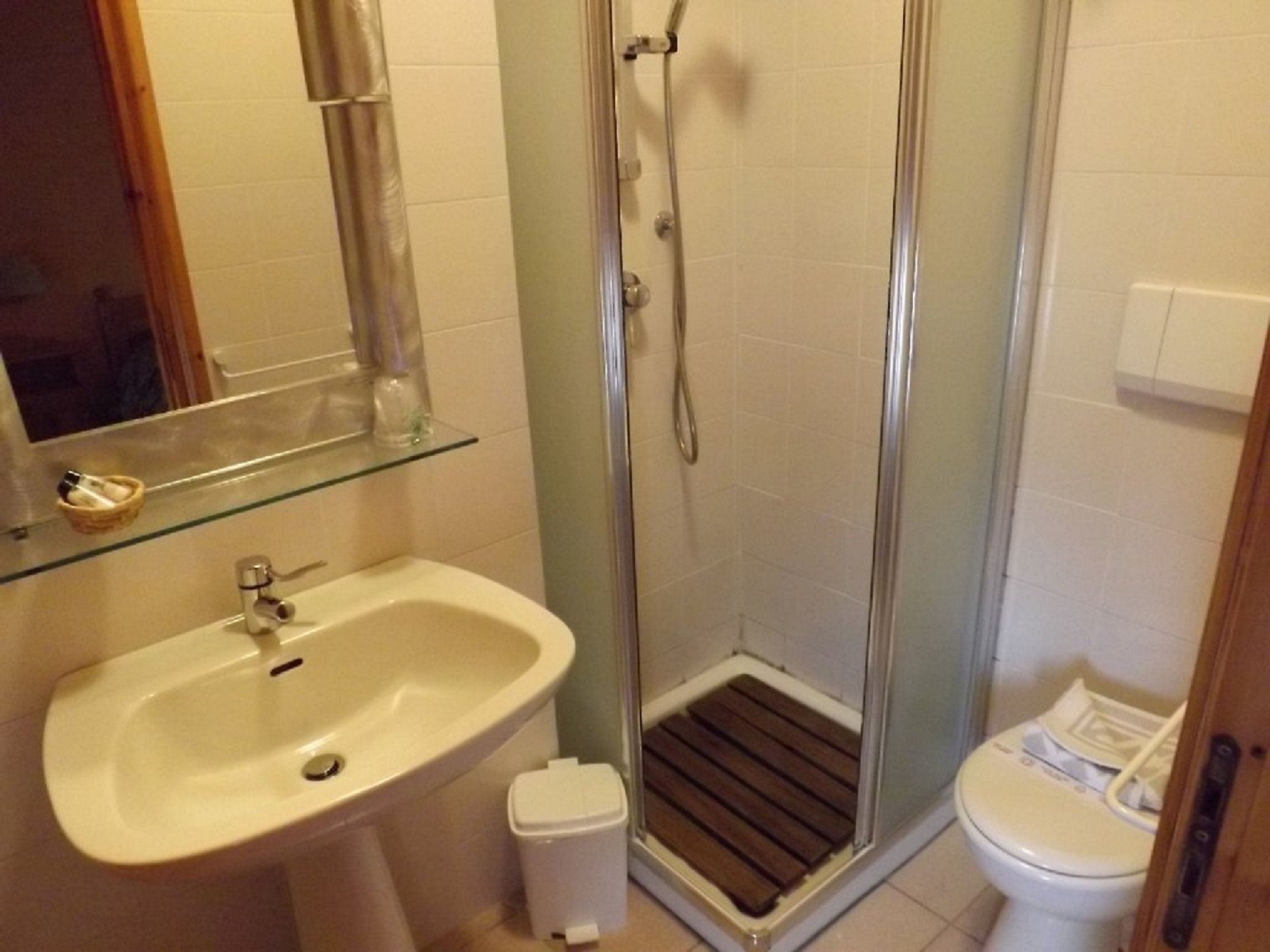 A bathroom with a glass shower enclosure, a sink, and a toilet.