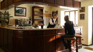 A bar area with wooden cabinetry, a counter, and a bar stool. - Hotel Lion (Roure)