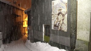 A snow-covered alleyway with a poster on a wall. - Hotel Lion (Roure)