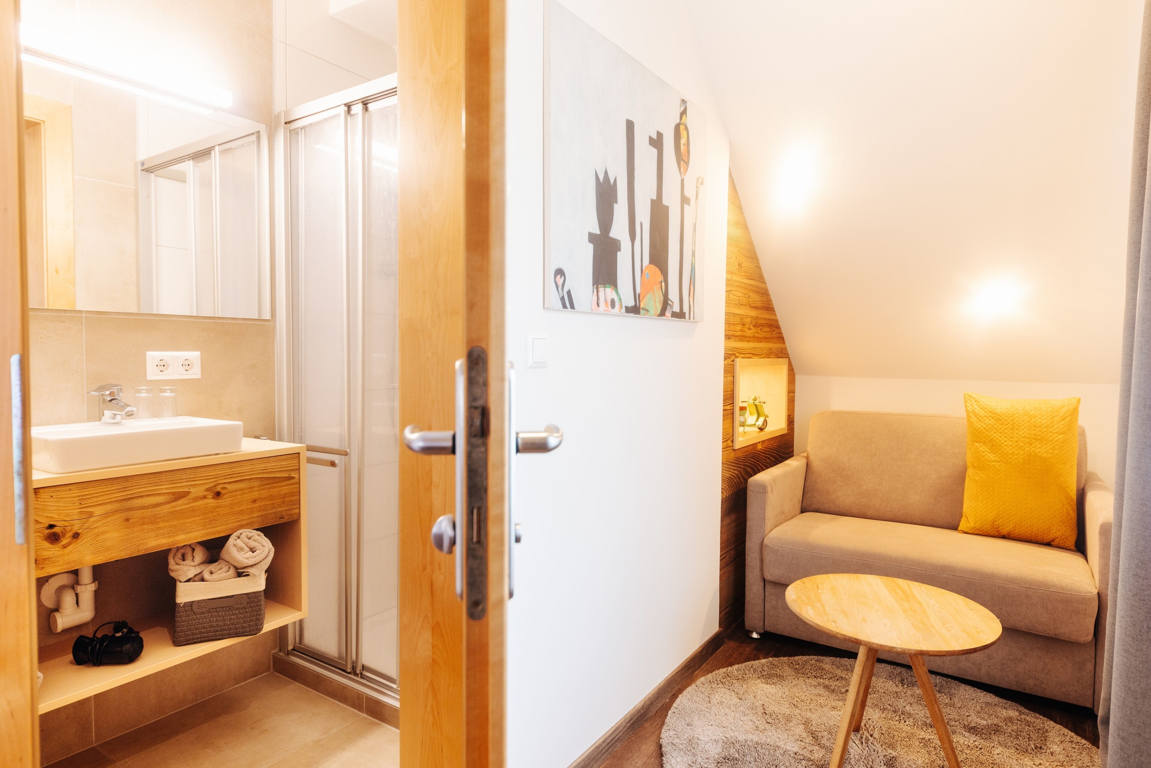 Un baño moderno con tocador de madera, un lavabo y una ducha.