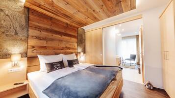 A modern bedroom with a wooden headboard, a large bed, a nightstand, and a bedside lamp.