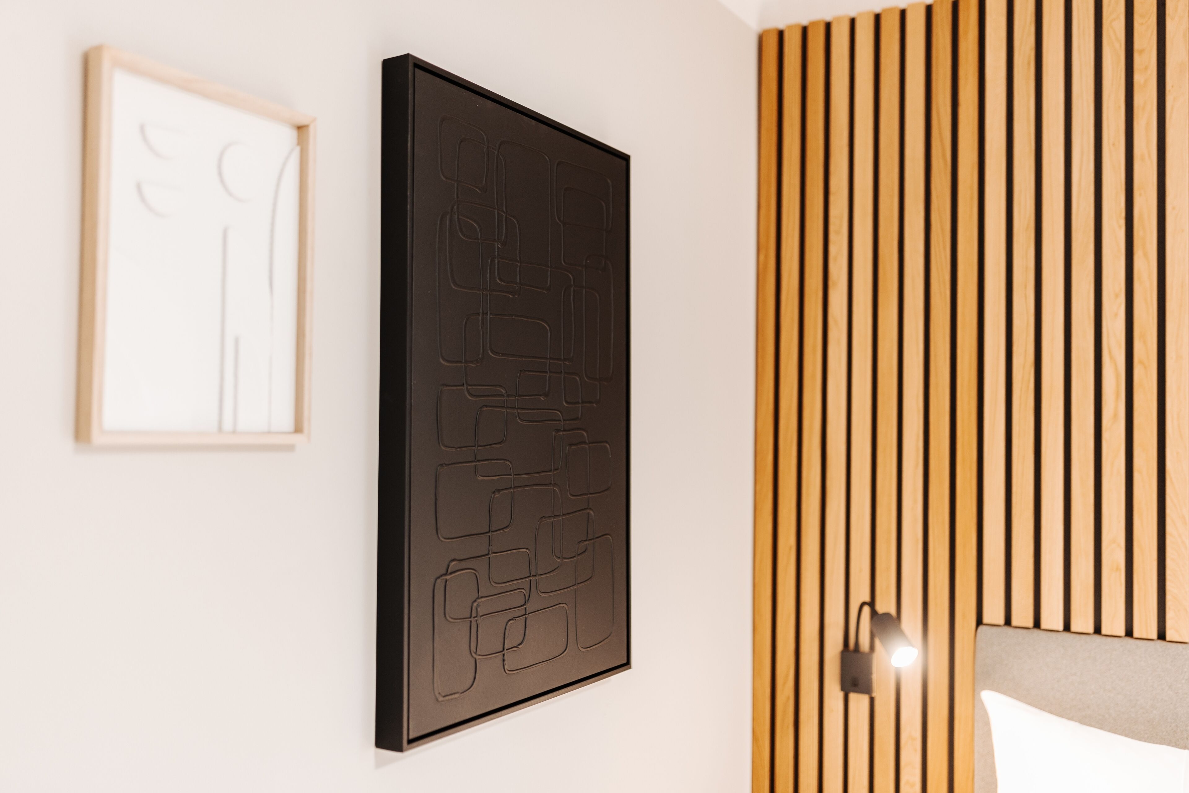 Een moderne kamer met een wand van houten latten, een lijst met abstracte kunst, en een lamp.