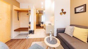 A modern living room with a sofa, a small round table, and a hallway leading to a bedroom.