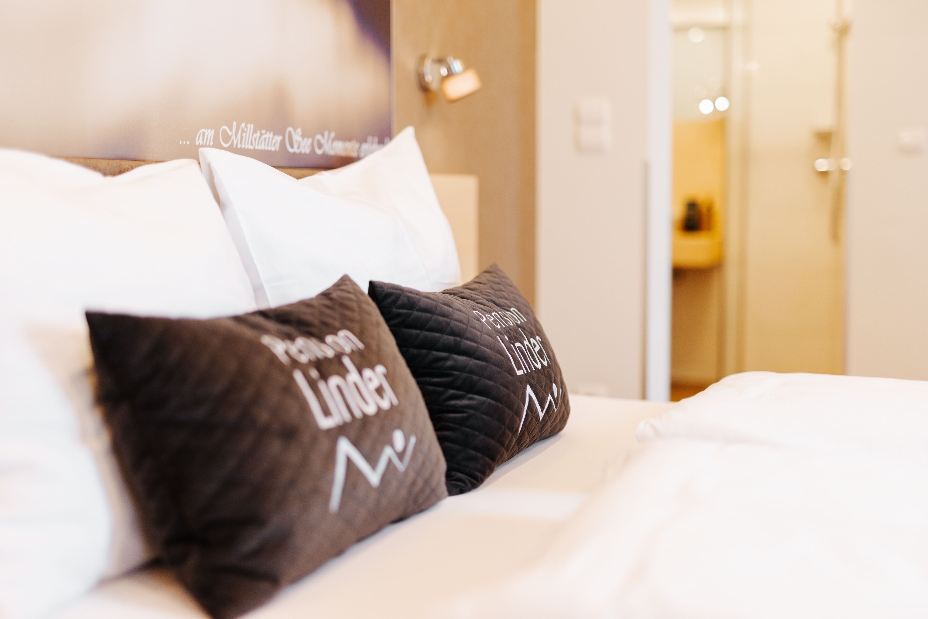 Una cama con dos almohadas, una con texto y otra con un diseño.