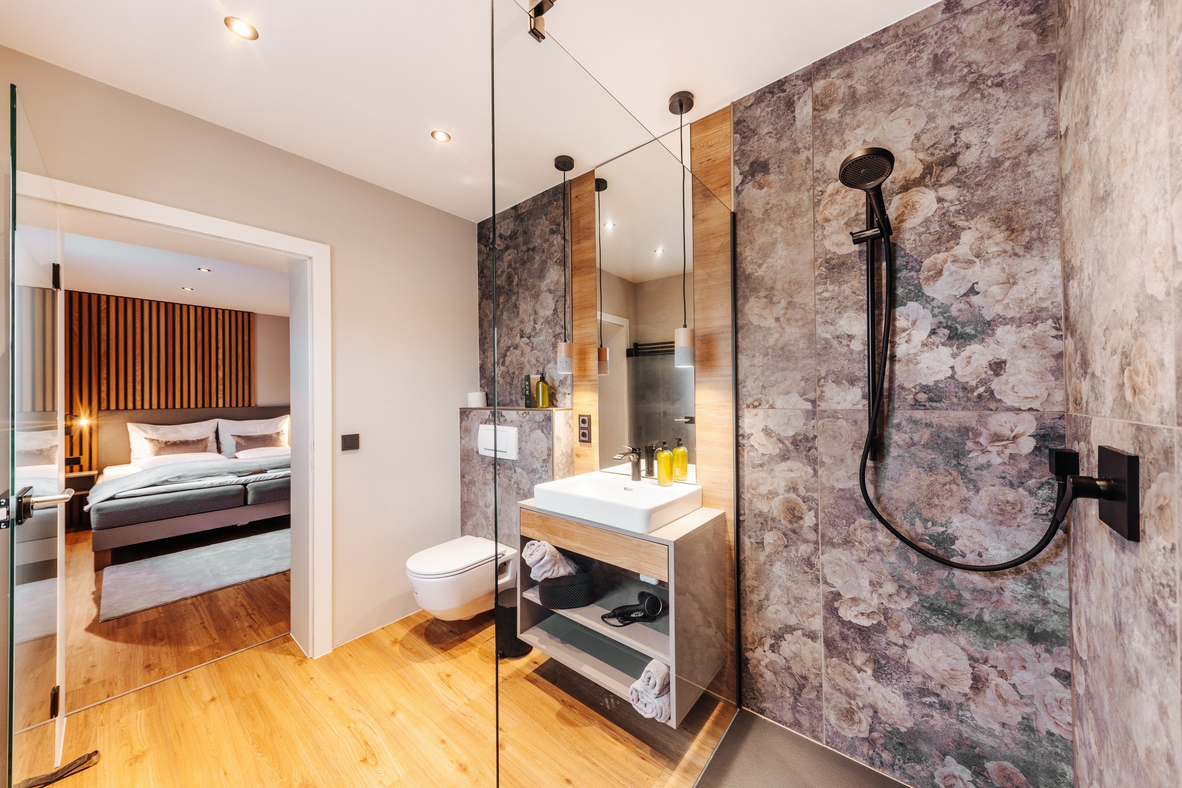 Ein modernes Badezimmer mit Dusche, ein Schlafzimmer mit Glaskonstruktion und Holzboden.