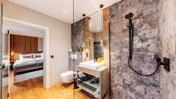 Ein modernes Badezimmer mit Dusche, ein Schlafzimmer mit Glaskonstruktion und Holzboden.