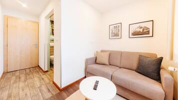 A modern living room with a beige sofa, a round white coffee table, and two framed pictures on the wall.